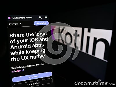 Person holding mobile phone with webpage of programming language Kotlin on screen in front of logo. Editorial Stock Photo