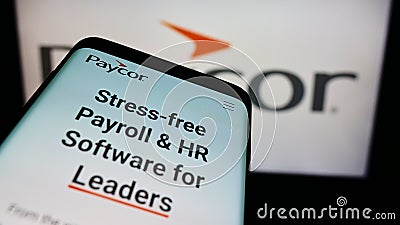 Person holding mobile phone with webpage of US HR software company Paycor HCM Inc. on screen in front of logo. Editorial Stock Photo