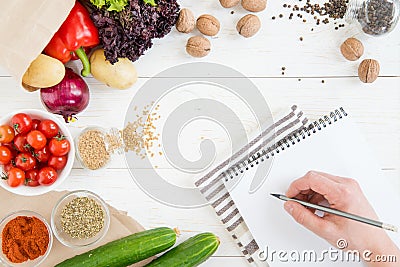 Person holding pencil and writing recipe in cookbook while cooking Stock Photo