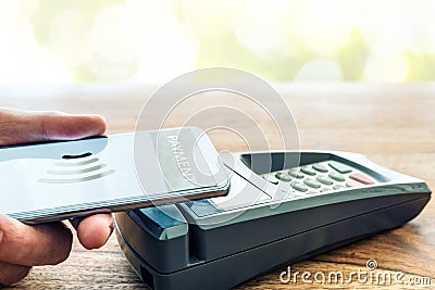 Person holding phone against POS payment terminal Editorial Stock Photo