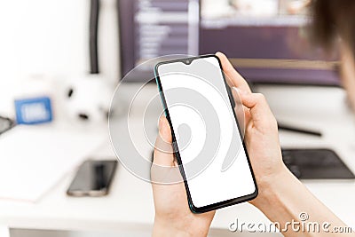 Person holding phone with blank screen in hands at work desk Stock Photo