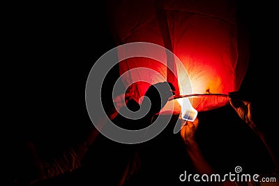 Person holding a red sky lantern with the flames showing clearly Stock Photo