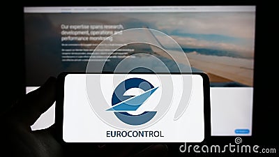 Person holding smartphone with logo of air traffic management organization Eurocontrol on screen in front of website. Editorial Stock Photo