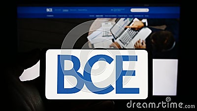 Person holding smartphone with logo of Canadian telecommunications company BCE Inc. on screen in front of website. Editorial Stock Photo