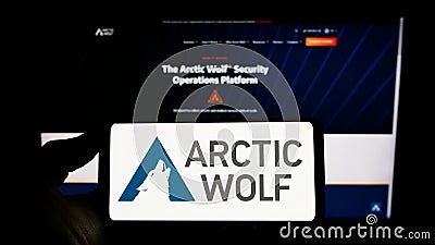 Person holding smartphone with logo of cybersecurity company Arctic Wolf Networks Inc. on screen in front of website. Editorial Stock Photo