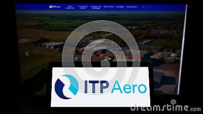Person holding smartphone with logo of Industria de Turbo Propulsores S.A. (ITP Aero) on screen. Editorial Stock Photo