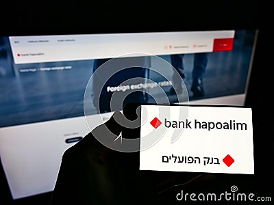 Person holding smartphone with logo of Israeli financial company Bank Hapoalim BM on screen in front of business webpage. Editorial Stock Photo