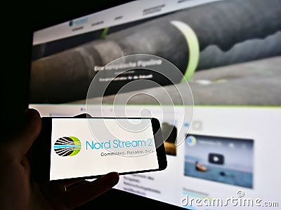 Person holding smartphone with logo of offshore natural gas pipeline project Nord Stream 2 in North Sea. Editorial Stock Photo