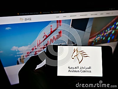 Person holding smartphone with logo of shopping mall operator Arabian Centers Company (ACC) on screen with website. Editorial Stock Photo
