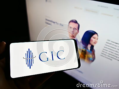 Person holding smartphone with logo of Singaporean sovereign wealth fund GIC Private Limited on screen in front of website. Editorial Stock Photo