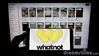 Person holding smartphone with logo of US e-commerce company Whatnot Inc. on screen in front of website. Editorial Stock Photo