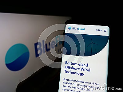 Person holding smartphone with webpage of Spanish renewables company BlueFloat Energy LLC on screen with logo. Editorial Stock Photo