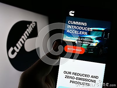 Person holding smartphone with webpage of US manufacturing company Cummins Inc. on screen in front of logo. Editorial Stock Photo