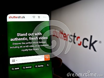 Person holding smartphone with webpage of US stock photography company Shutterstock Inc. on screen with logo. Editorial Stock Photo
