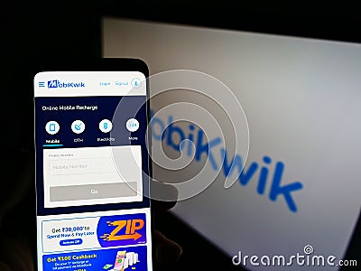 Person holding smartphone with website of Indian financial technology company MobiKwik on screen in front of logo. Editorial Stock Photo
