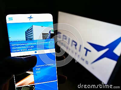 Person holding smartphone website logo of US aviation company Spirit AeroSystems Inc. on screen in front of logo. Editorial Stock Photo