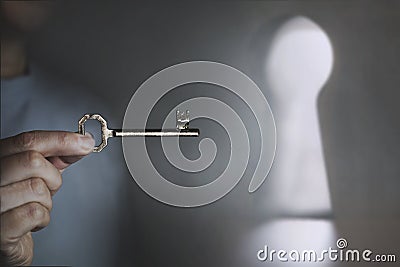 Person holds in hand the key that will perhaps open the door to freedom Stock Photo