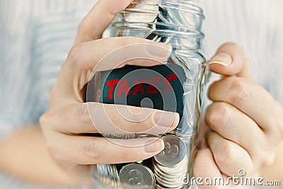 Person holds taxes deduction in glass jar. Stock Photo