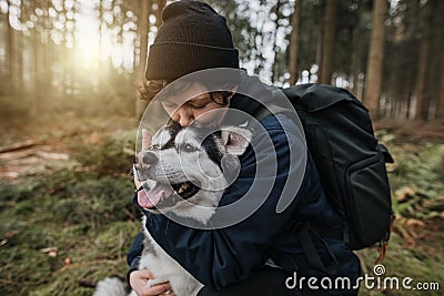 person hugs and kisses his black white dog in the forest Stock Photo