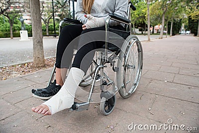 Person injured in a wheelchair. Foot and hand bandages, outdoor photography in a park Stock Photo