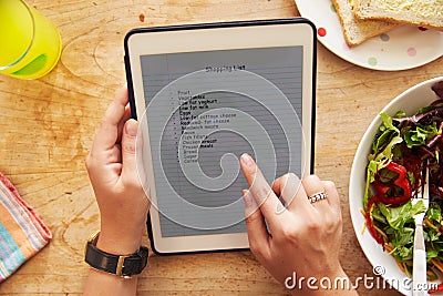 Person At Lunch Looking At To Do List On Digital Tablet Stock Photo