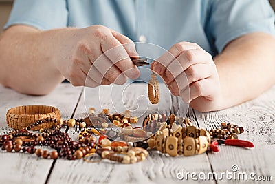 Person making earings from colorful beads and needles Stock Photo