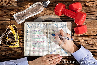 Person Making Note Of Workout Plan On Notebook Stock Photo