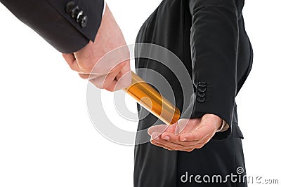 Person passing a golden relay baton to another person Stock Photo