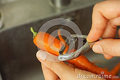 Person peeling a carrot with a peeler Stock Photo