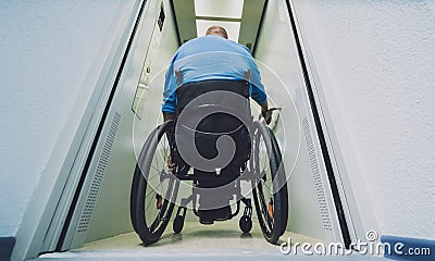 Person with a physical disability in a wheelchair using lift in building Stock Photo