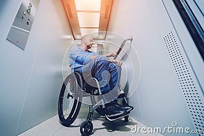 Person with a physical disability who uses wheelchair using lift in building Stock Photo