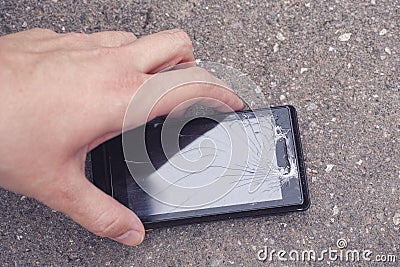 Person picking up a cracked smartphone Stock Photo