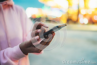 Person pointing finger on screen smartphone on defocus background bokeh light in evening street, hipster girl using in hands mobil Stock Photo