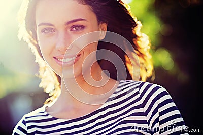 Person, portrait and smile with nature, sunset and park for happiness and wellness. Woman, joy and sunshine with closeup Stock Photo
