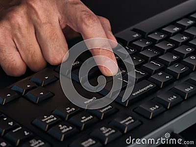 A person pressing the enter key on a black keyboard Stock Photo