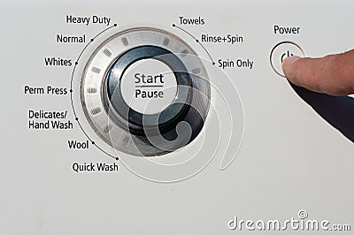 A person pressing the power button on a washing machine Stock Photo