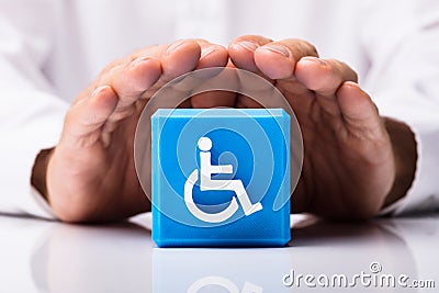 Person Protecting Cubic Block With Disabled Icon Stock Photo