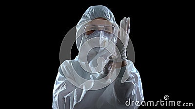 Person in protective suit wearing rubber gloves against dark background, toxins Stock Photo