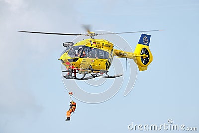 Person rappels down from a hovering ADAC rescue helicopter, in flight shot. Editorial Stock Photo