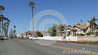 Person riding bicycle, palm trees and people in coastal pacific resort Oceanside, California USA. Editorial Stock Photo