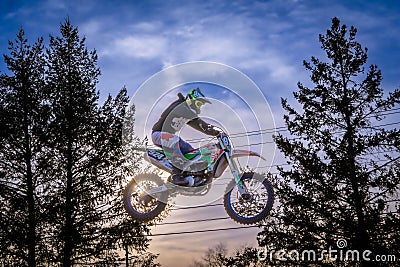 a person riding a dirt bike in the air over trees Editorial Stock Photo