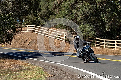 Person riding a motorcycle down a winding road. Editorial Stock Photo