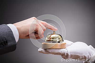 Person Ringing Service Bell Held By Waiter Stock Photo