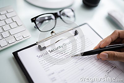 Person's Hand Filling Social Security Benefits Application Stock Photo