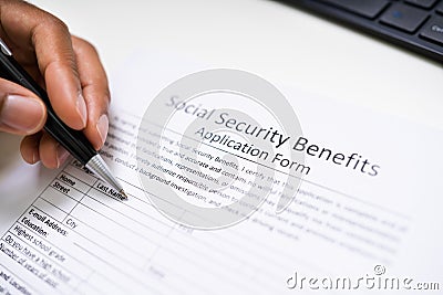 Person`s Hand Filling Social Security Benefits Application Form Stock Photo