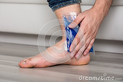 Person`s Hand Holding Ice Gel Pack On Ankle Stock Photo