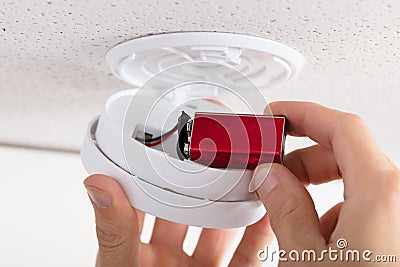 Person`s Hand Inserting Battery In Smoke Detector Stock Photo