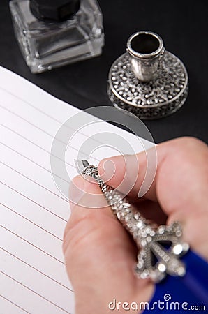 Person`s Hand Writing with a Metal Fountain Pen with Gall Bottle and Pen Holder Stock Photo