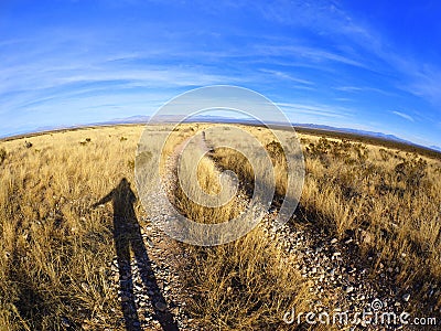 Shadow of Person in Afternoon Sun Along a Dirt Road in an Arizona Arid Desert Landscape Stock Photo