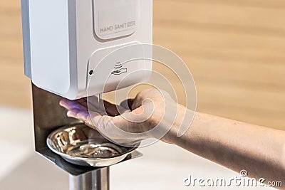 Person sanitizing hands with liquid gel from public sanitizing machine Stock Photo